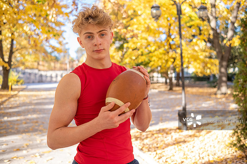 活跃的小男孩在公园里玩美式橄榄球图片素材