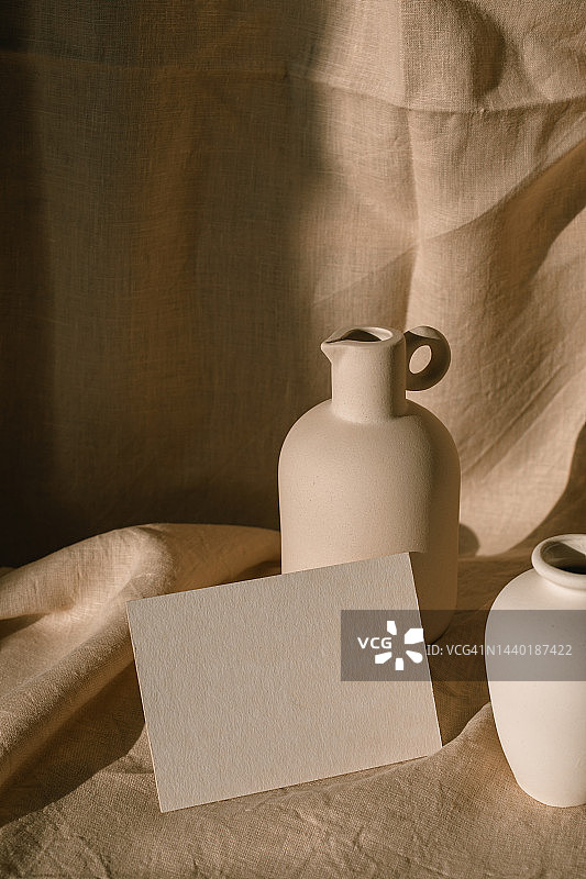 一张空白卡片的特写旁边的陶瓷壶和花瓶在桌子上图片素材