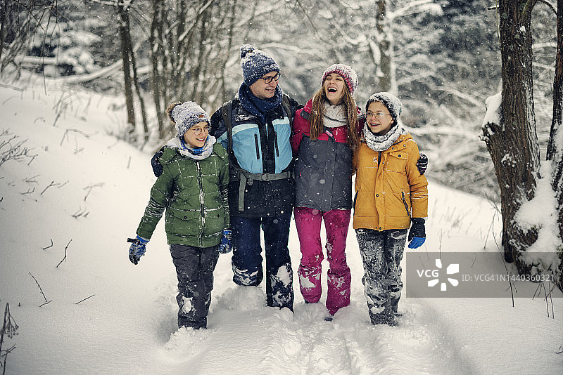 父亲带着十几岁的孩子在美丽的冬季森林里徒步旅行。图片素材