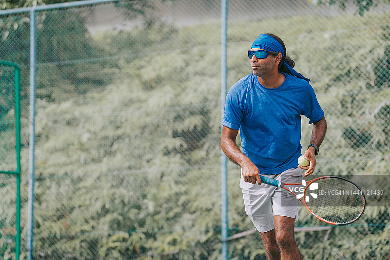 亚洲印度男子网球运动员在硬地网球比赛中打网球图片素材