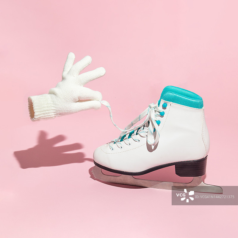 冬天的创意布局与滑板和手套持有鞋花边在柔和的粉色背景。八九十年代的复古美学假日概念。最小季节的想法。图片素材