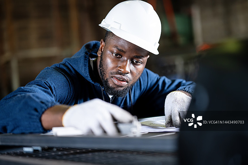 质量控制确保定制金属加工。非裔美国男性工业工程师在工厂使用游标卡尺测量焊接后的金属零件。图片素材