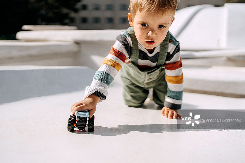 可爱的幼童在户外玩汽车玩具图片素材