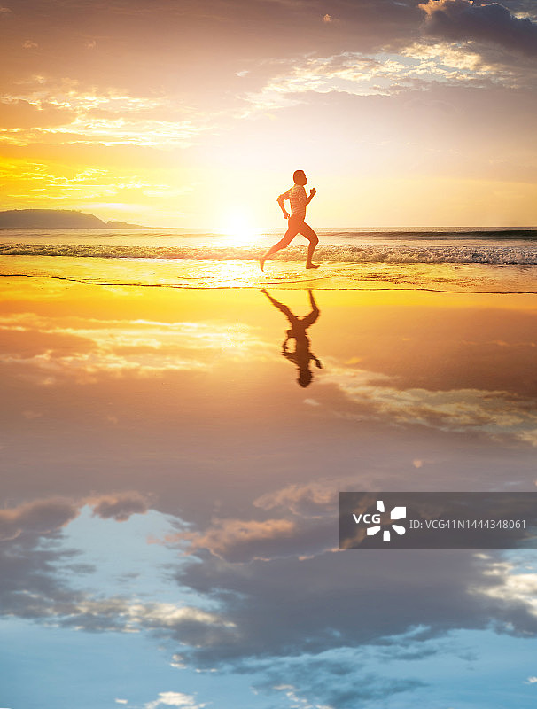 亚洲年轻人在日落时分在海滩上跑步图片素材