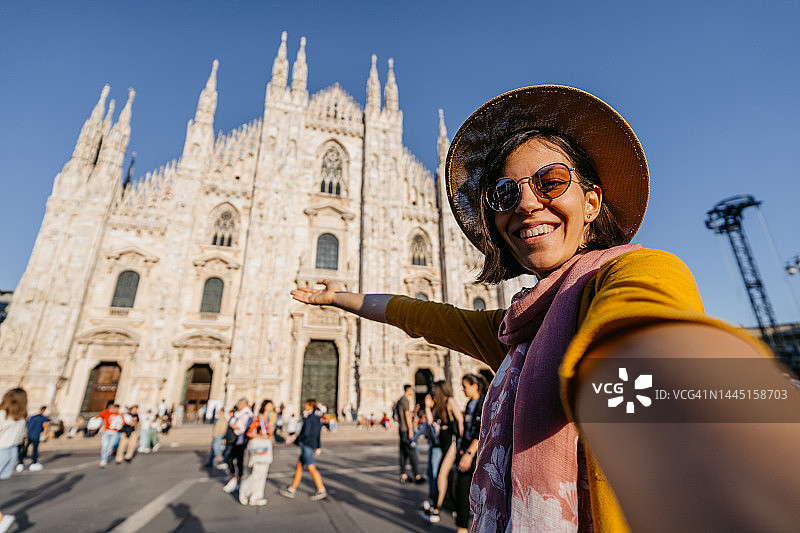 年轻的女游客在米兰大教堂前进行视频通话图片素材