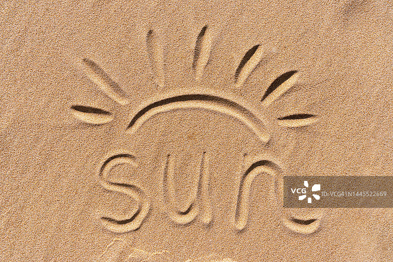 “太阳”是手写的文字，太阳光线画在海边的金色沙滩上。图片素材