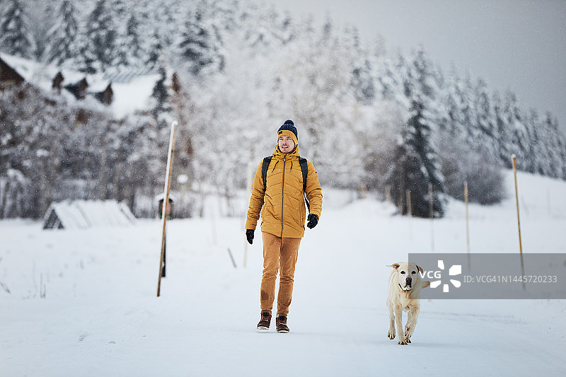 男子与狗在冬天的一天在雪景图片素材