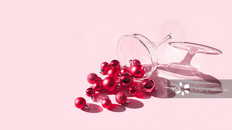 鸡尾酒杯和圣诞装饰球红色Viva品红色2023年颜色在柔和的粉色背景。图片素材