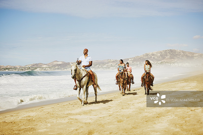 大范围拍摄的家庭骑马在热带海滩度假图片素材