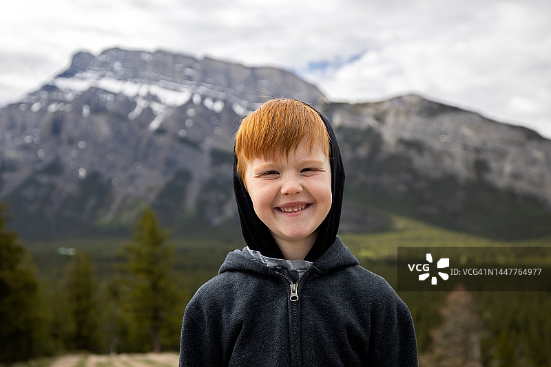 年轻的6岁红发男孩微笑着，看着相机徒步旅行图片素材