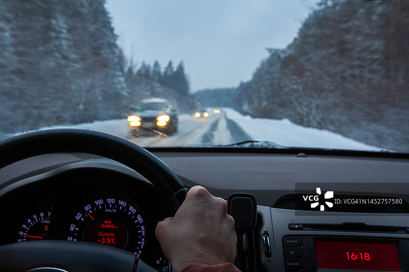 冬天的驾驶-透过挡风玻璃在一个下雪的道路在黄昏图片素材