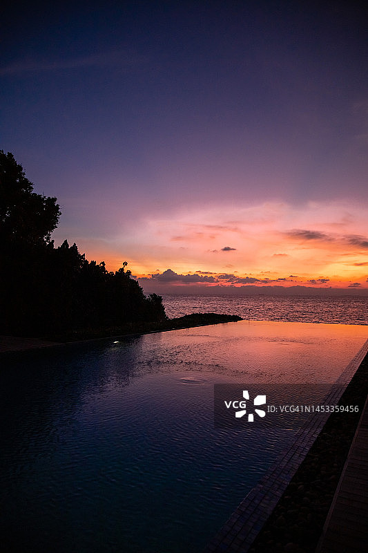 浪漫多彩的日落在无边泳池与阳光反射在马尔代夫的热带岛屿上的水图片素材