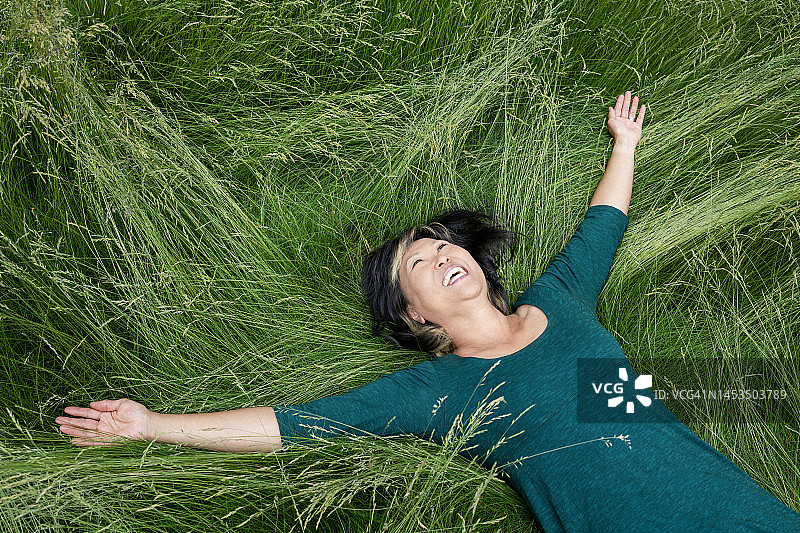 成熟的女人躺在高高的草丛里笑图片素材