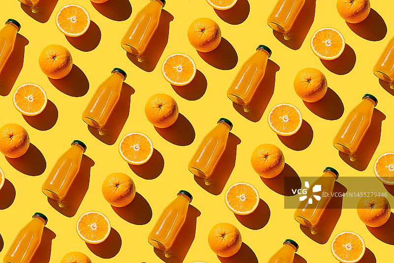 色彩鲜艳的鲜榨橙汁瓶子，新鲜的原料橙在黄色背景上。超级食品，健康食品，饮料，饮食和排毒概念。平铺，俯视图图片素材