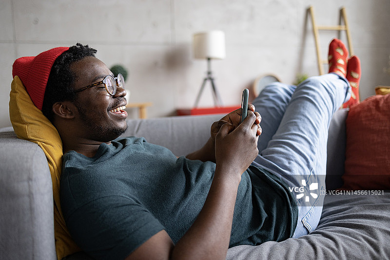 快乐的非裔美国人在家里使用智能手机图片素材