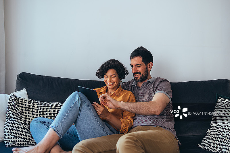 一对幸福美丽的夫妇在家休息时，用平板电脑上的应用程序学习一门新语言图片素材