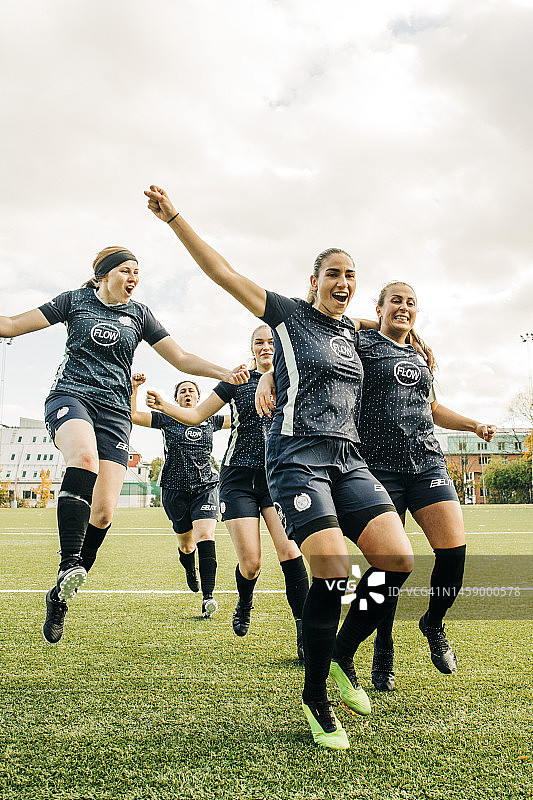 在体育场举行的足球比赛中，快乐的女球员们跳在一起庆祝进球图片素材