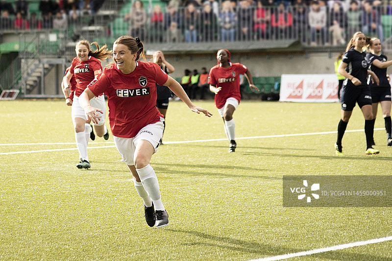 快乐的女子足球运动员在比赛中进球后奔跑图片素材