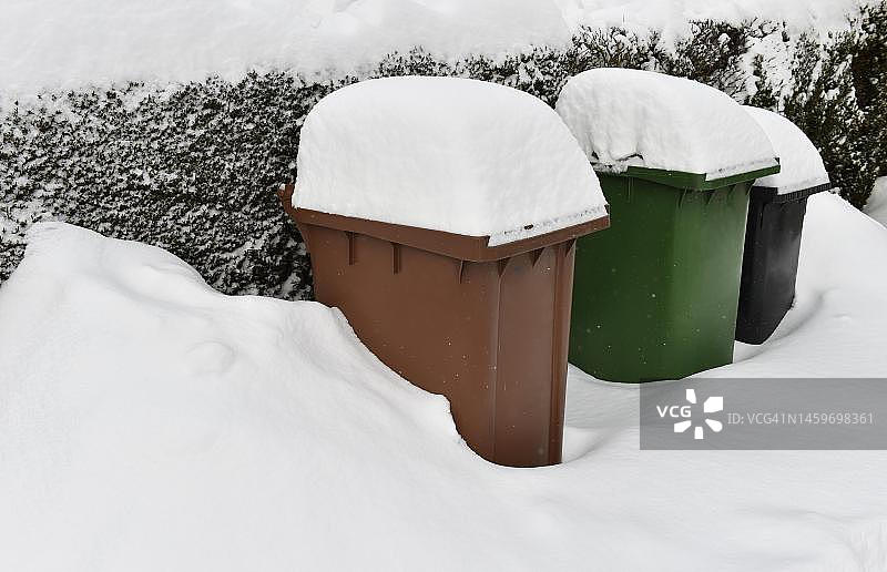 德国黑森州Vellmar被雪覆盖的垃圾箱，有机垃圾箱和废纸垃圾箱图片素材