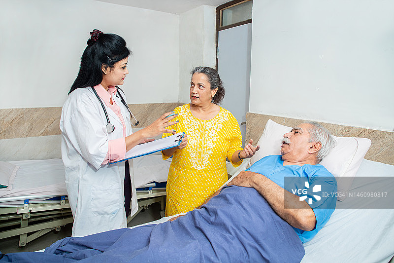 印度医生在诊所或医院与老年男性病人的妻子讨论如何改善她丈夫的健康状况，老年人的保健理念。图片素材