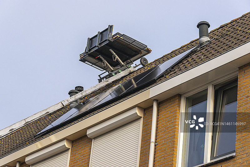 在屋顶安装太阳能电池板时，梯子上的移动平台图片素材