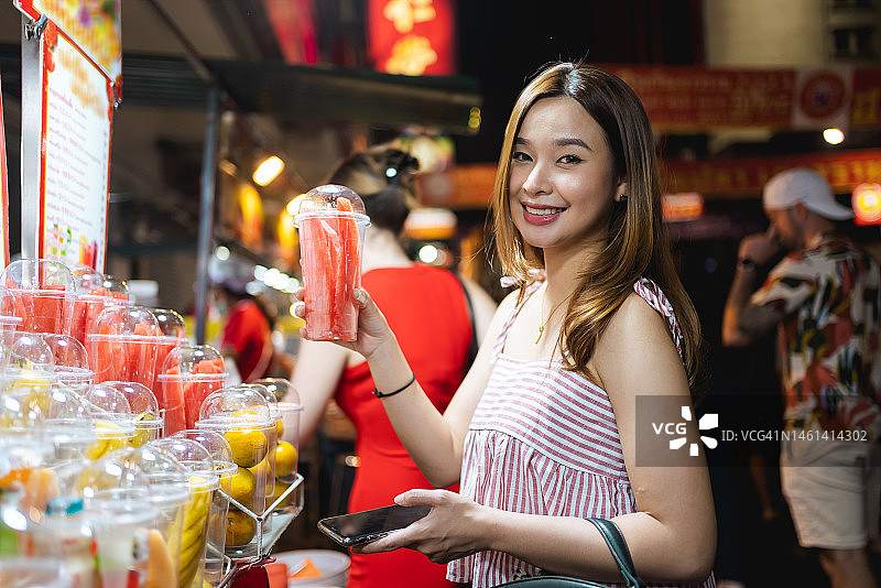年轻的亚洲妇女在曼谷唐人街购买冰沙饮料图片素材