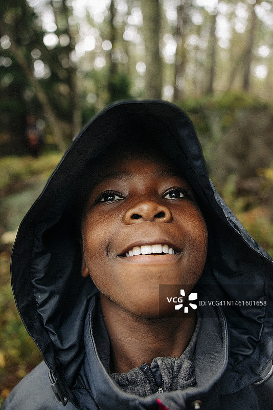 在森林里穿着雨衣的体贴男孩望向远方图片素材