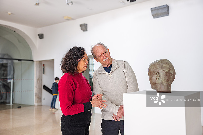 不同的老夫妇在博物馆里看雕像时正在交谈图片素材