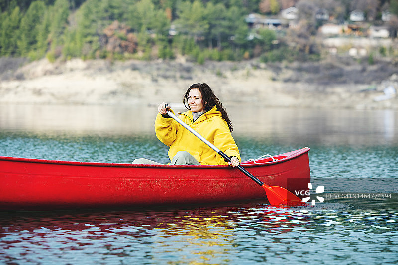 一个年轻的成年女子独自在湖边划独木舟图片素材
