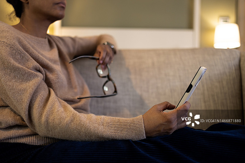 黑人妇女在沙发上休息时使用智能手机图片素材