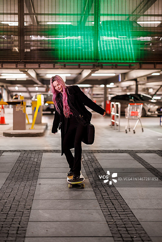 一个美丽的女人在夜晚的城市街道上玩滑板，玩得很开心。图片素材