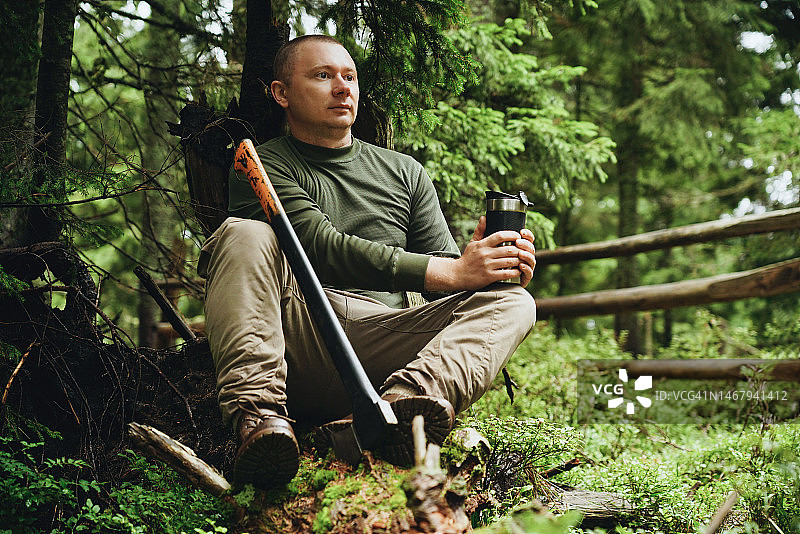 一个人拿着斧头在森林里休息图片素材