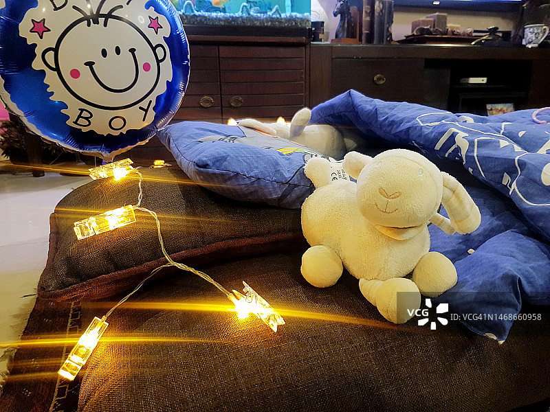 一个男孩出生时，客厅里有点亮的仙女灯、氦气球和毛绒玩具。图片素材