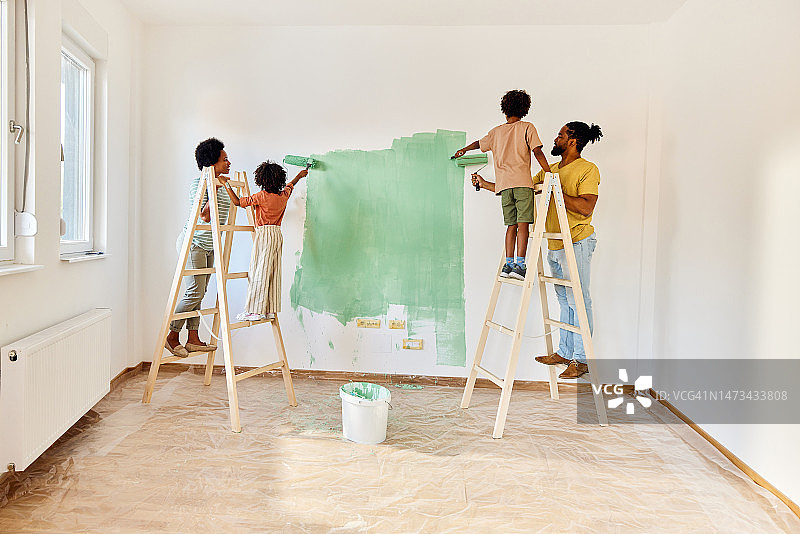 非裔美国家庭在公寓的墙壁上画画。图片素材