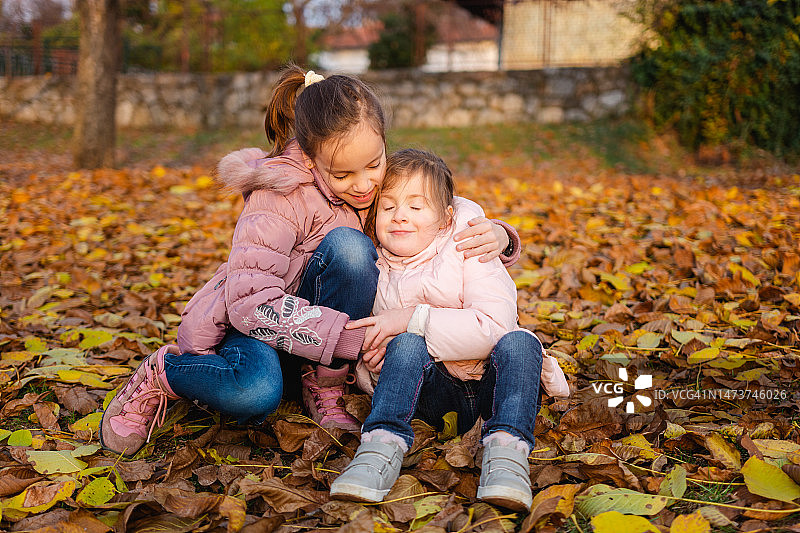 秋天公园里快乐的女孩们拥抱在一起图片素材