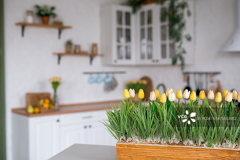 白色的桌子上放着一束郁金香。背景是斯堪的纳维亚风格的白色厨房内部。家庭舒适的概念。图片素材