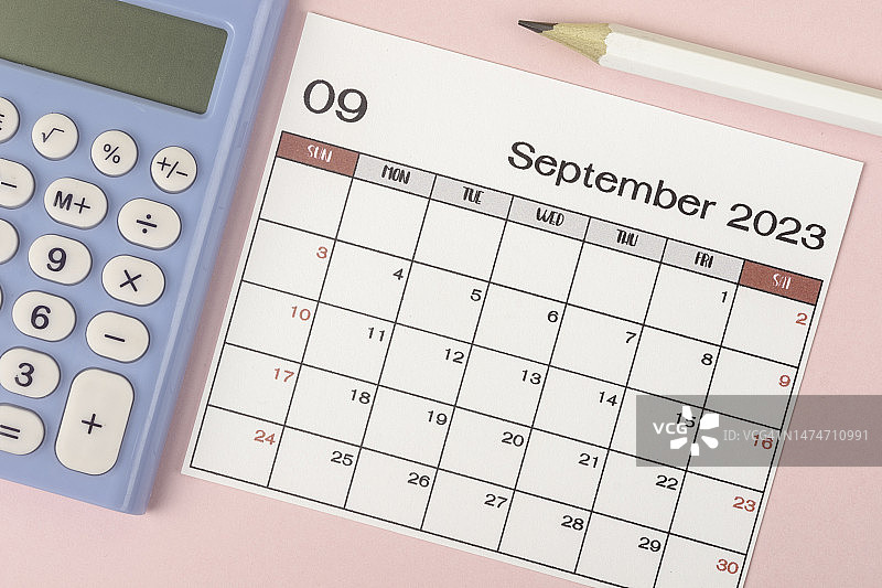 2023日历台:9月是组织者在灰色纸张背景下，用白色铅笔和计算器来计划和截止日期的月份。图片素材