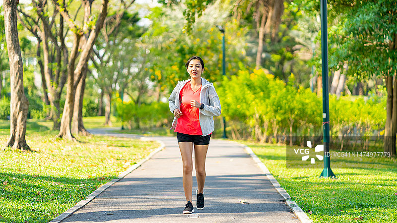亚洲女子早上在公园慢跑。图片素材