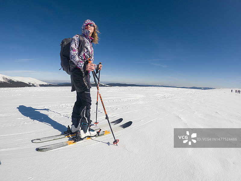 年轻的白人女子滑雪旅行在一个阳光灿烂的日子。天空中的冒险女人图片素材