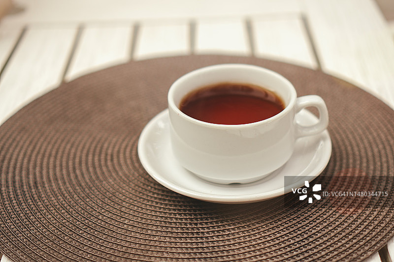 白色陶瓷杯，茶托上有红茶。舒适的特写自然热饮复制空间。正面，高角度拍摄图片素材