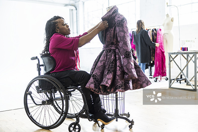 女服装设计师坐在轮椅上调整服装造型图片素材