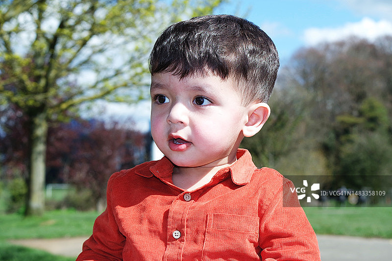 英国卢顿，靠着树站着的可爱男孩的特写图片素材