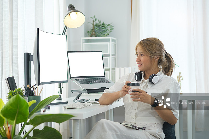 微笑的女性IT开发人员的肖像，坐在白色现代办公室内部的大型弯曲电脑显示器前。图片素材