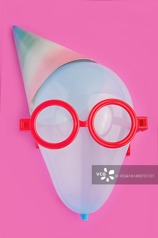 贺卡。气球在眼镜与节日帽接近粉红色的背景。图片素材