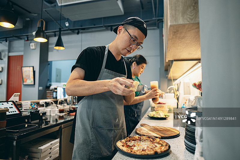 两名亚洲餐厅的工作人员正在厨房工作，合作制作美味的饭菜。图片素材