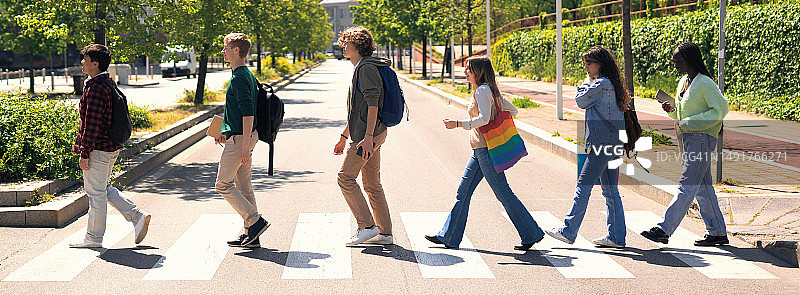 一群年轻的学生去上大学，走在城市的大街上。图片素材