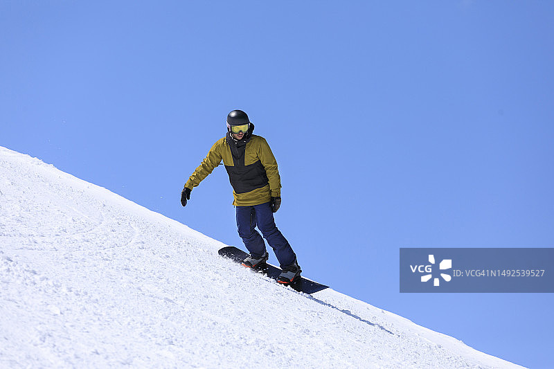 一个年轻人在高山滑雪场上玩单板滑雪图片素材