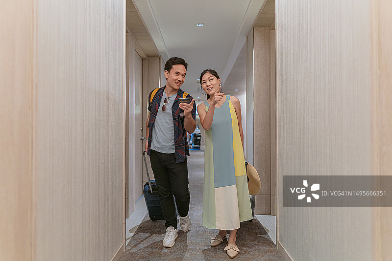 快乐的亚洲夫妇正从酒店走廊走向他们的房间图片素材