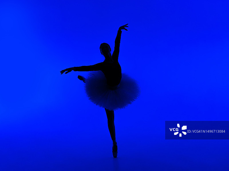 芭蕾舞者在蓝色背景下跳舞的完整长度图片素材