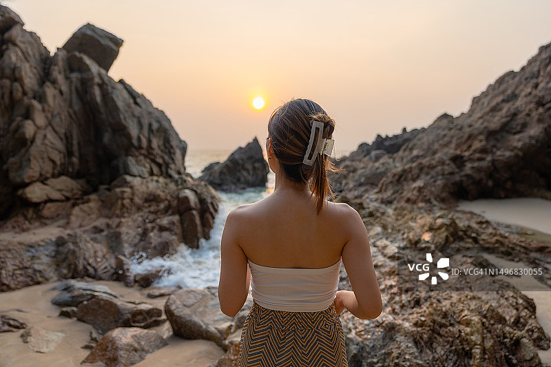 在普吉岛的秘密海滩上，一名女子走在海岸线上看日落图片素材